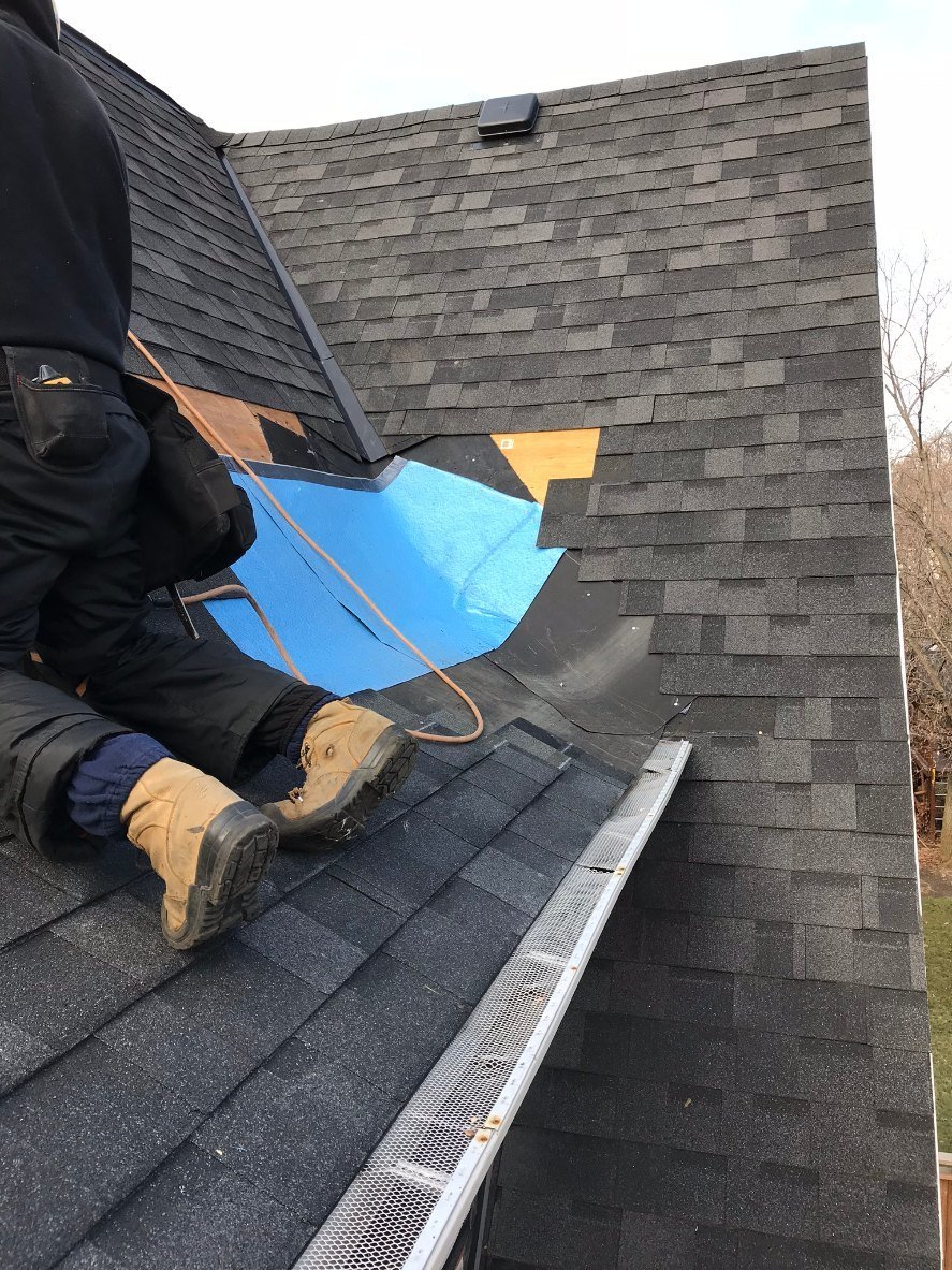 Roofer repairing damaged shingles mid-tear-off